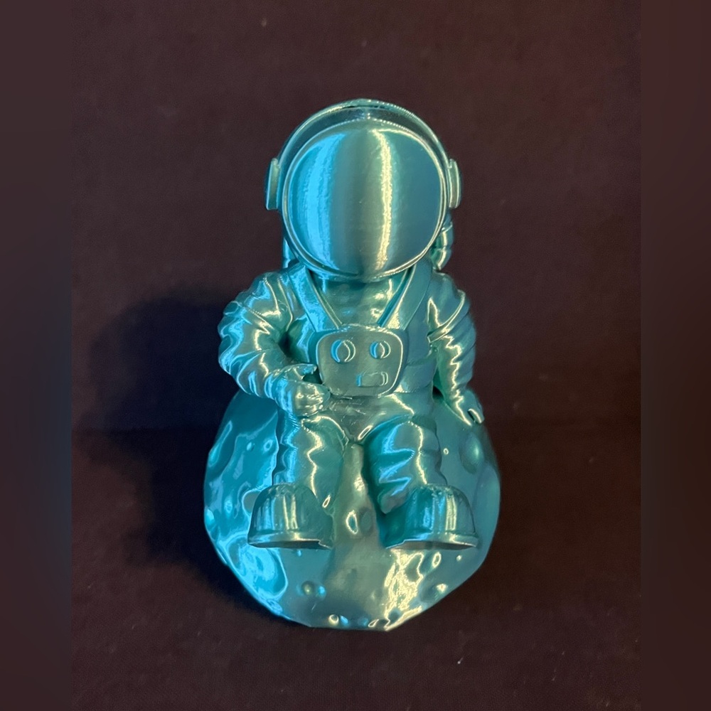 3D Printed Teal Astronaut Figure sitting on the moon